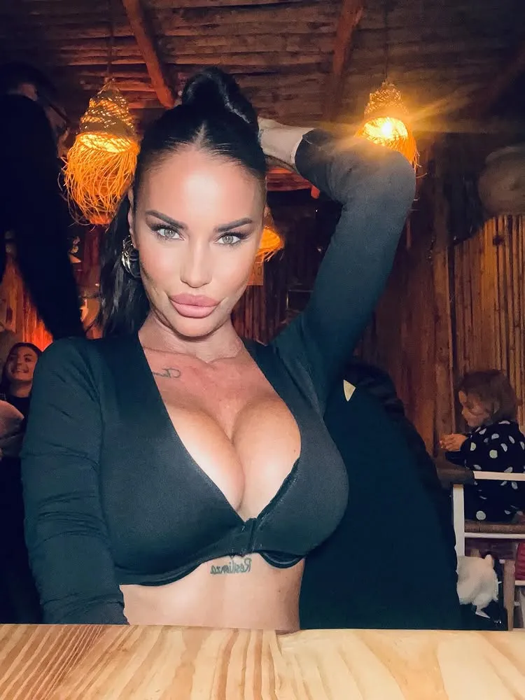 Antonella Mosetti posing in black top with deep cleavage inside a rustic restaurant
