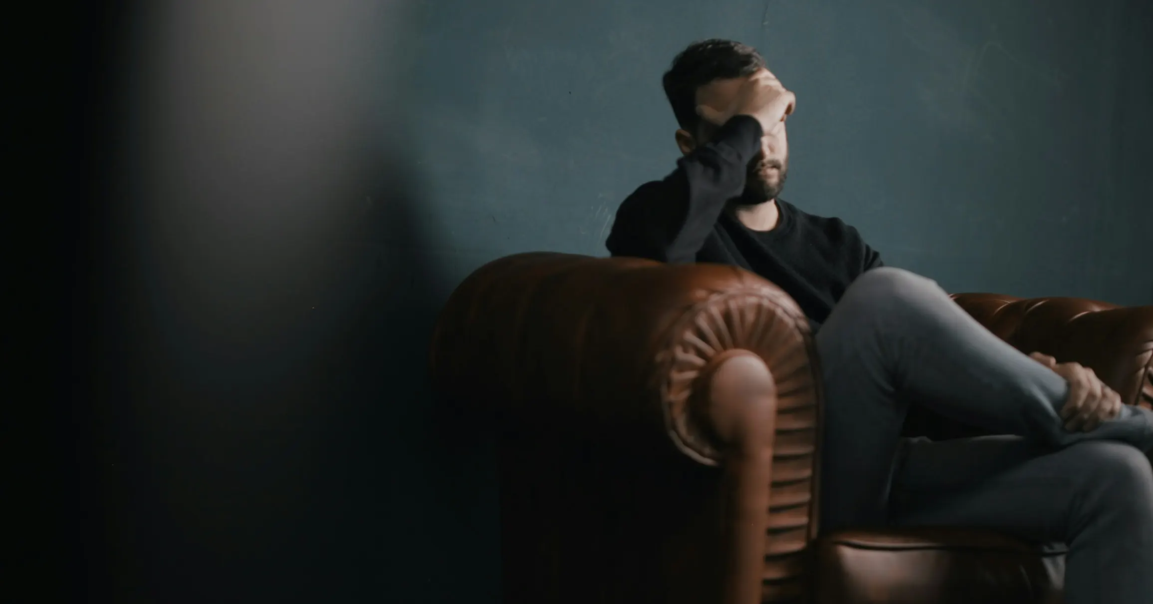 A man sits in a chair, head in hands, reflecting on the emotional impact of paying for sex online.