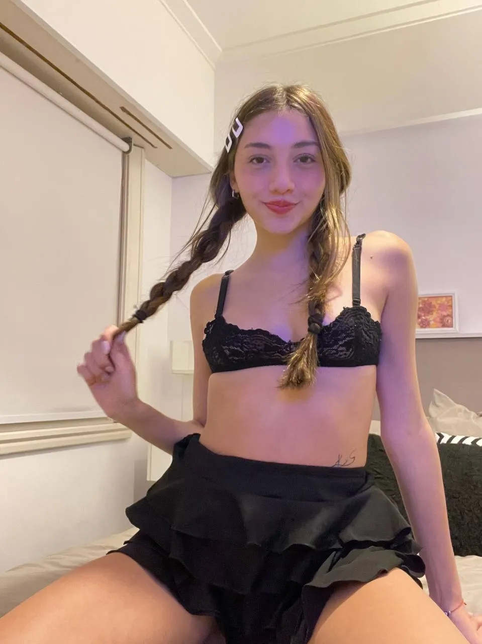 Skinny model posing in a bedroom with black lace clothing and braided hairstyle